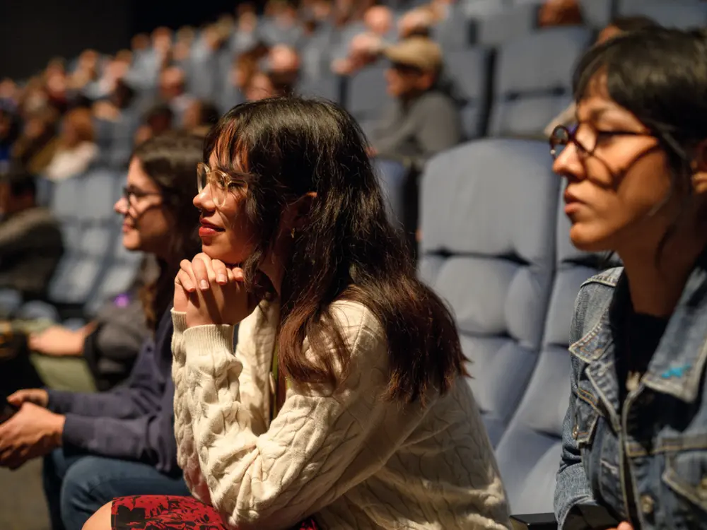 Women sit in rapt attention in the cushy seats of the theater's stadium seating. 