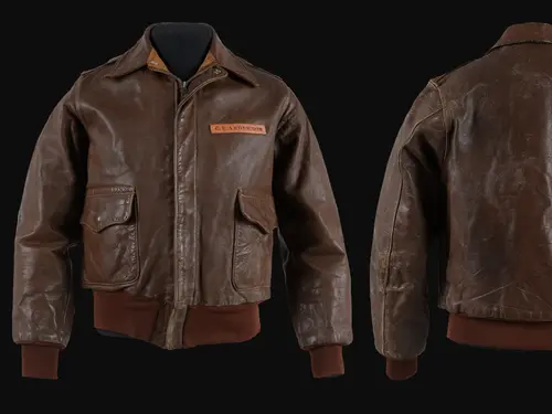 A brown leather jacket viewed from the front and back situated side by side against a black backdrop.