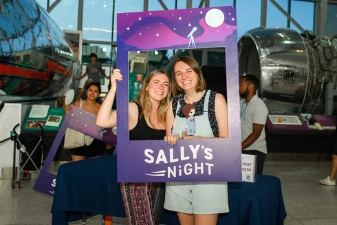 Two women photographed in a frame that celebrates Sally's Night.