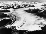 An aerial photograph of what looks to be a white river, but is actually a glacier cutting through the land.