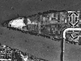 An aerial photo of a triangular shaped island that has a bridge connecting it to the mainland.