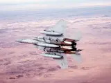 A U.S. Air Force F-15 fighter jet flying over a desert landscape.