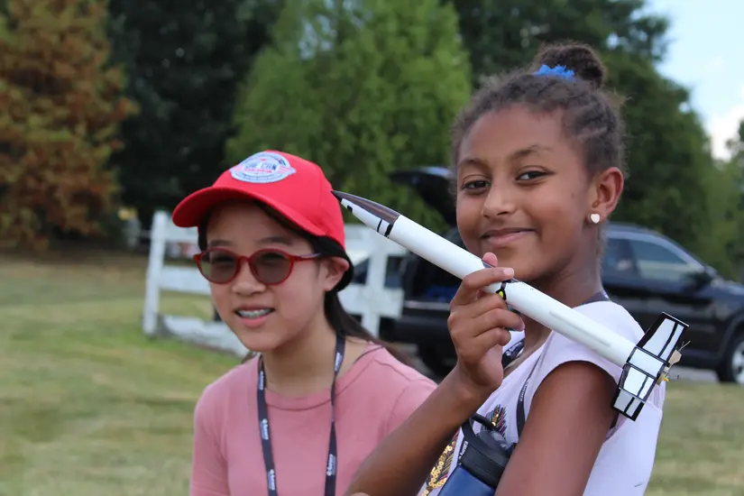 A young girl shows off a small rocket.