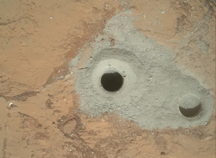 The surface of Mars with a hole bored into it. 