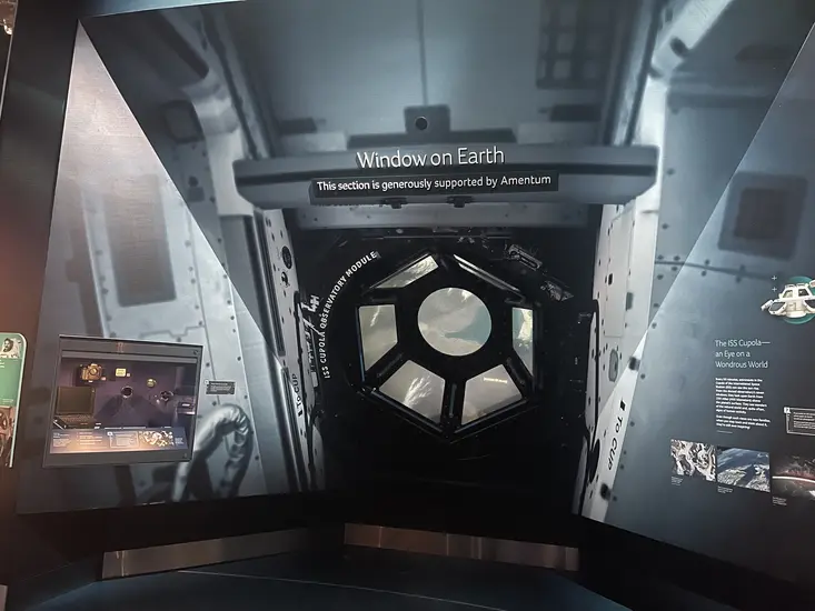 A wall with an indented section that features a dome shaped window. The window shows different views of the earth from space.