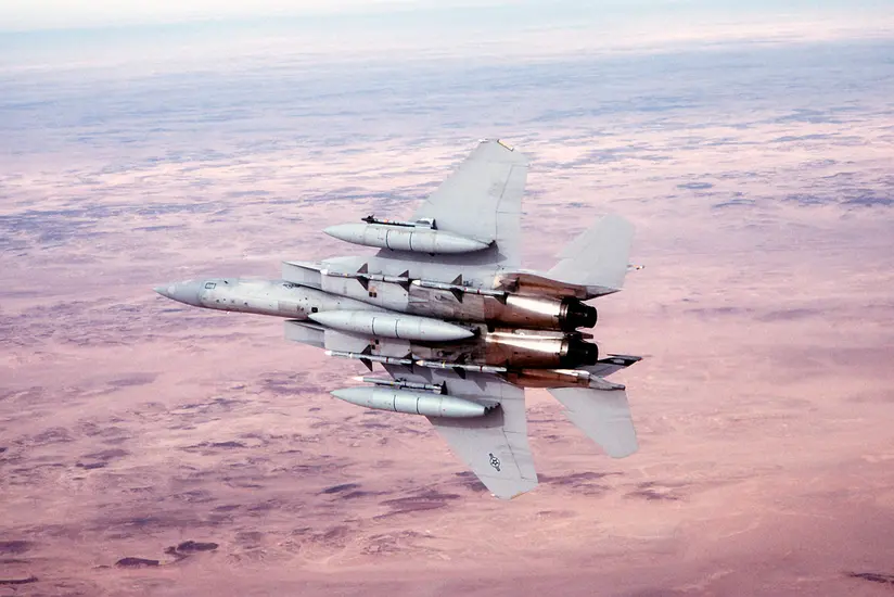 A U.S. Air Force F-15 fighter jet flying over a desert landscape.